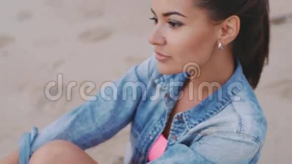 美丽的女孩坐在沙滩上视频的预览图