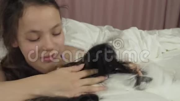 快乐少女亲吻和玩狗帕皮隆在床上股票视频视频的预览图
