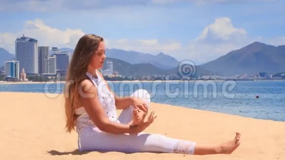 穿着白色蕾丝服装的女孩在海滩上展示瑜伽体式儿童姿势视频的预览图