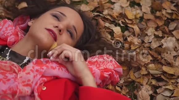 女孩的肖像躺在公园的秋叶上视频的预览图