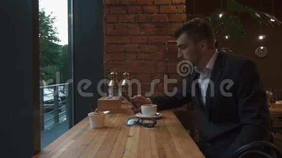 灵感来自一杯新鲜咖啡英俊的年轻人拿着手机坐着喝咖啡视频的预览图
