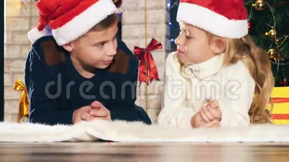 男孩和女孩躺在圣诞树附近的地板上视频的预览图