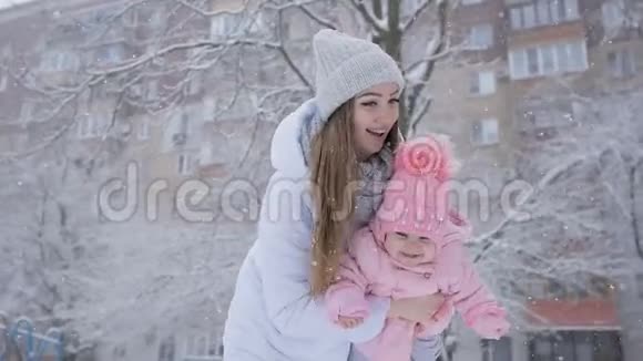 年轻的母女在公园的大雪中幸福地在一起视频的预览图