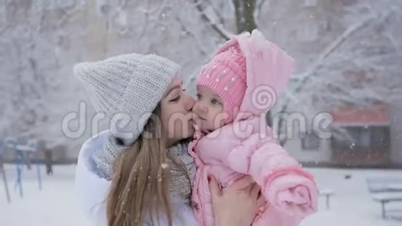 年轻的母女在公园的大雪中幸福地在一起视频的预览图