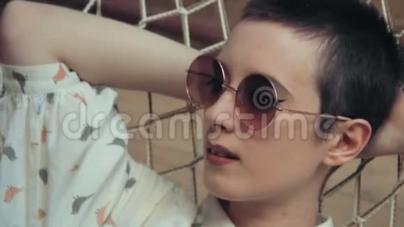 短发女人戴着眼镜在阁楼公寓的吊床上放松视频的预览图