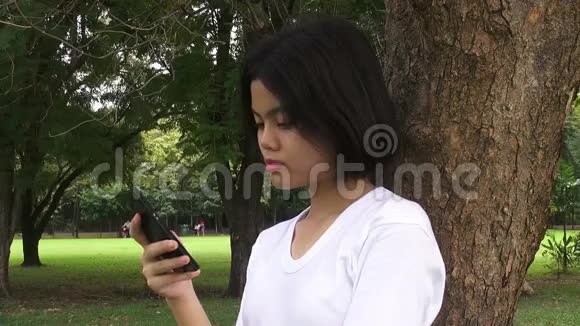美丽的年轻时髦女人在秋季公园使用智能手机穿着秋装的漂亮姑娘发短信视频的预览图