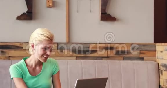 漂亮的金发女郎用她的笔记本电脑喝咖啡视频的预览图