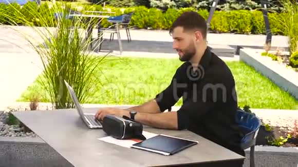 快乐商人用笔记本电脑在外面工作用虚拟现实眼镜享受视频的预览图