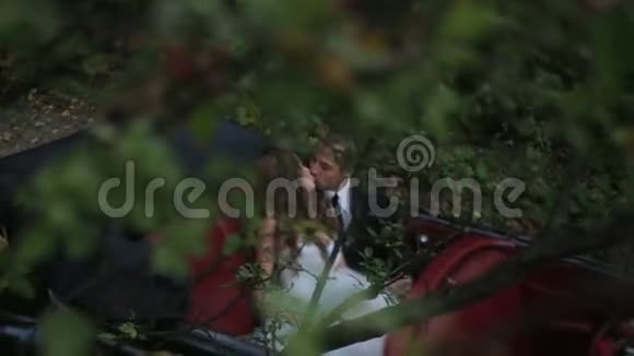 新婚夫妇在亲密的气氛中在复古车后座接吻视频的预览图