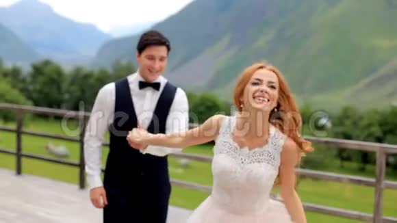 结婚纪念日幸福的新婚夫妇在群山的背景下玩得很开心视频的预览图