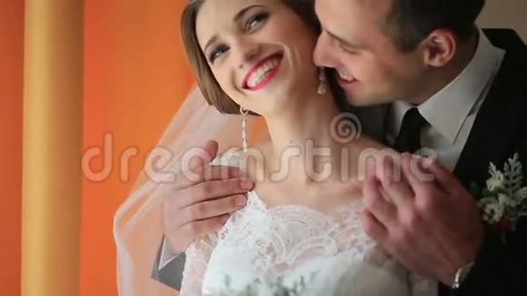 美丽的年轻夫妇迷人的新娘捧着婚礼花束可爱的新郎拥抱和亲吻视频的预览图