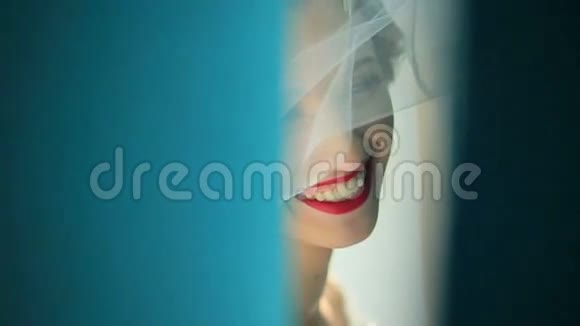 迷人的害羞新娘在镜头前微笑躲在蓝色窗帘后面的肖像视频的预览图