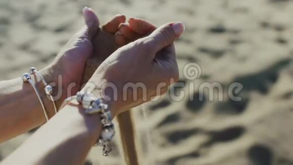 沙滩上的沙子从女人的手中涌出视频的预览图