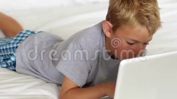 小男孩在床上用笔记本电脑视频的预览图