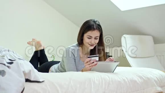 使用数码平板电脑躺在家里的女人视频的预览图