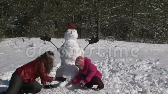 妈妈蹲在女儿和雪人旁边视频的预览图