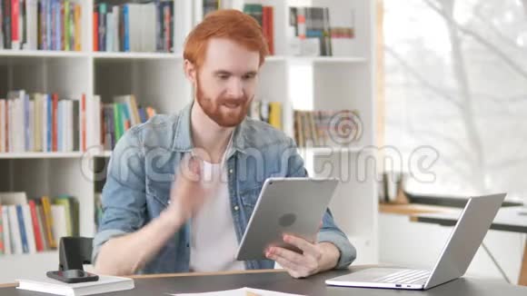 休闲红发男子在桌上讲视频聊天视频的预览图