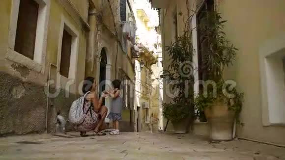 母亲在希腊一条狭窄的街道上给女儿编辫子视频的预览图
