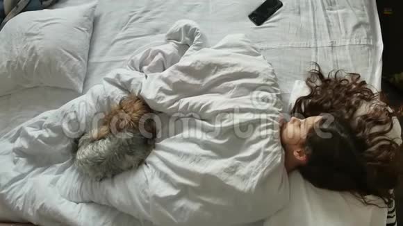 小可爱的女孩和睡在床上的毛茸茸的狗一个小女孩和一只睡得很香的小狗一个浅黑色的小女孩睡着了视频的预览图