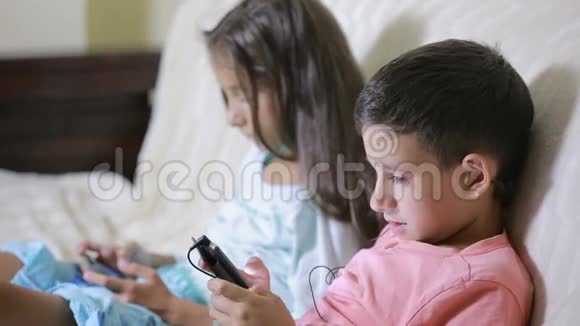 男孩和女孩拿着你的手机坐在沙发上网上游戏视频的预览图