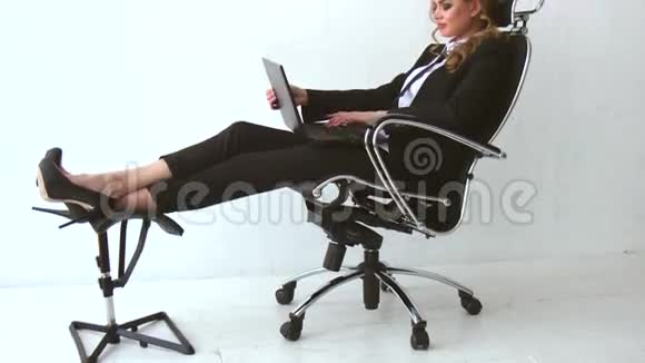 一个美丽的女孩坐在椅子上用笔记本电脑视频的预览图