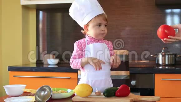 打扮成厨师的可爱的小宝宝帮助妈妈准备沙拉视频的预览图