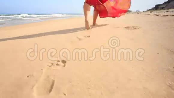 穿红色长裙的特写女郎在湿沙上留下脚印视频的预览图
