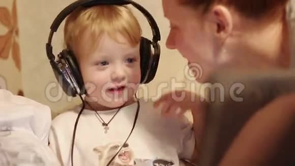 戴着耳机的小男孩听音乐亲吻妈妈视频的预览图