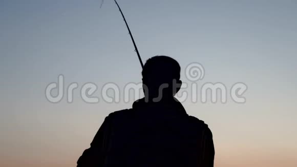 剪影渔夫在渔竿上钓鱼傍晚日落视频的预览图