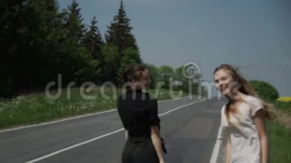 两个年轻的女搭便车者站在一旁要求停车视频的预览图