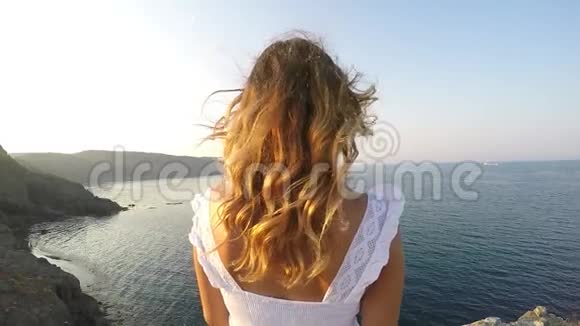 一个女孩看着大海她在山上日落视频的预览图