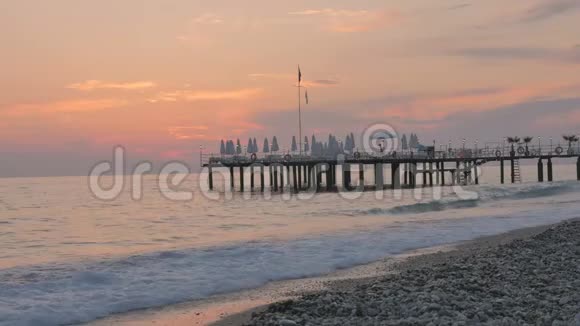 五颜六色的日落在海上美丽的卵石海滩有波浪和码头视频的预览图