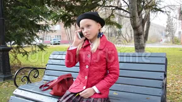 女孩坐在木凳上的公园里用智能手机说话自然场景视频的预览图