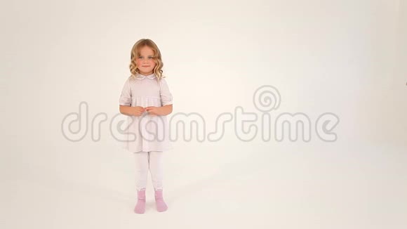 可爱的害羞的可爱的小女孩蹒跚学步的孩子卷发穿着白色连衣裙用手指在空中画着一颗大大的心视频的预览图