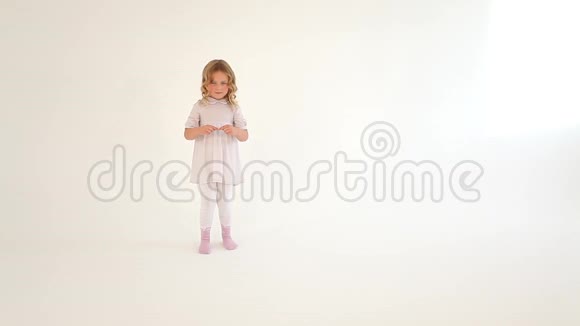 可爱的小害羞的小可爱的小女孩蹒跚学步的孩子卷发穿着白色连衣裙用手指在空中画出一颗大大的心视频的预览图