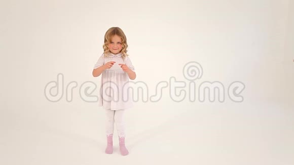 可爱的害羞的小可爱的小女孩蹒跚学步的孩子卷发穿着白色连衣裙用手指在空中画出一颗大大的心视频的预览图