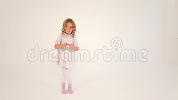 可爱的害羞的小可爱的小女孩蹒跚学步的孩子卷发穿着白色连衣裙用手指在空中画出一颗大大的心视频的预览图