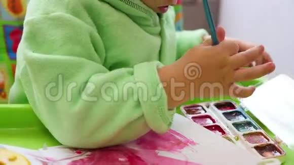 一个快乐的孩子用画笔在纸上画画视频的预览图