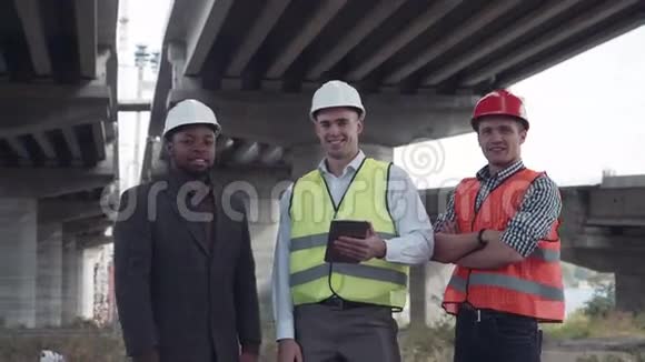 三个戴防护头盔的建筑师看着摄像机视频的预览图