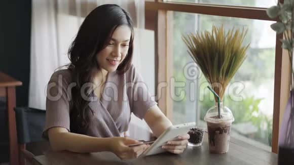 幸福的女人用信用卡在咖啡馆里用平板电脑上网购物视频的预览图