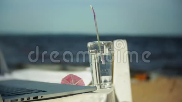 笔记本电脑和一杯水在俯瞰海洋的躺椅上视频的预览图