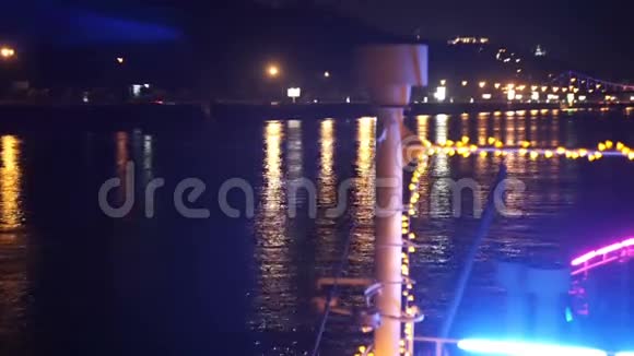 从装饰有花环的船上可以看到夜晚的城市堤岸景色视频的预览图