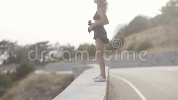 一个带着粉色头发的少女在一个带海景的山区的女儿墙上散步视频的预览图