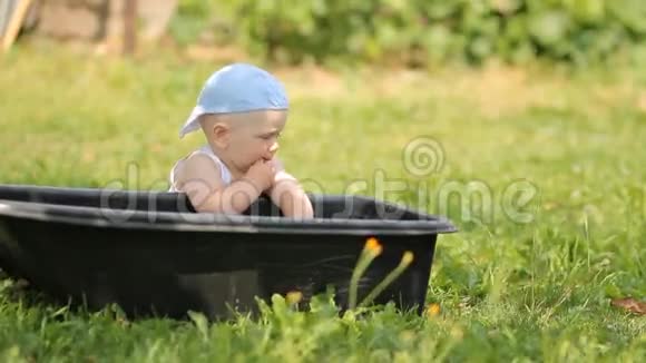 可爱的男孩在花园里玩一盆水他站起来微笑视频的预览图