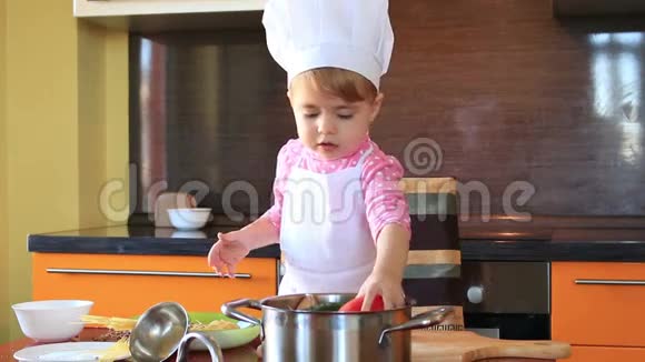 打扮成厨师的可爱的小宝宝帮助妈妈准备沙拉视频的预览图