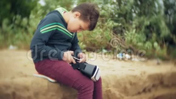 一个小男孩使用头盔作为虚拟现实耳机一个靠近旅游帐篷的海滩视频的预览图