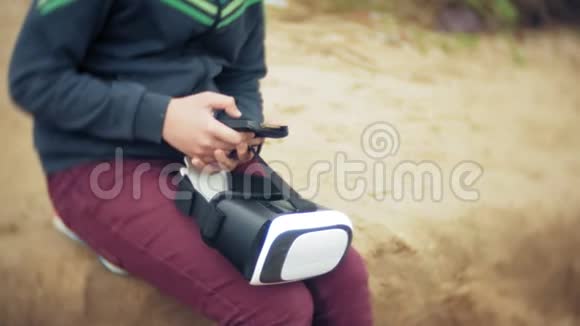 一个小男孩使用头盔作为虚拟现实耳机一个靠近旅游帐篷的海滩视频的预览图