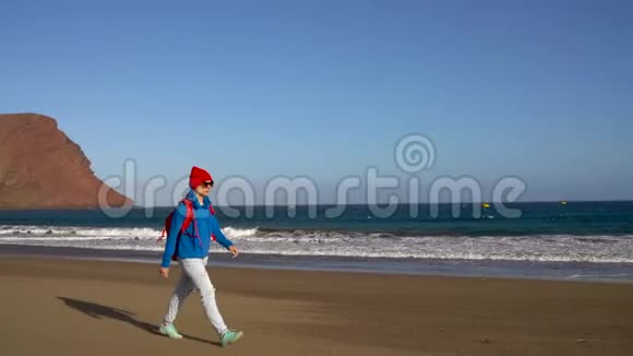 活跃的徒步旅行者女人在海滩上散步西班牙加那利群岛特内里费带背包的高加索年轻妇女视频的预览图