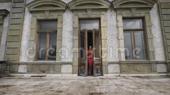 一个穿着红裙子的漂亮女孩在一个老庄园的阳台上视频的预览图