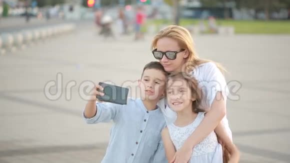 妈妈带着儿子和女儿正在做自拍手机上的家庭照片视频的预览图